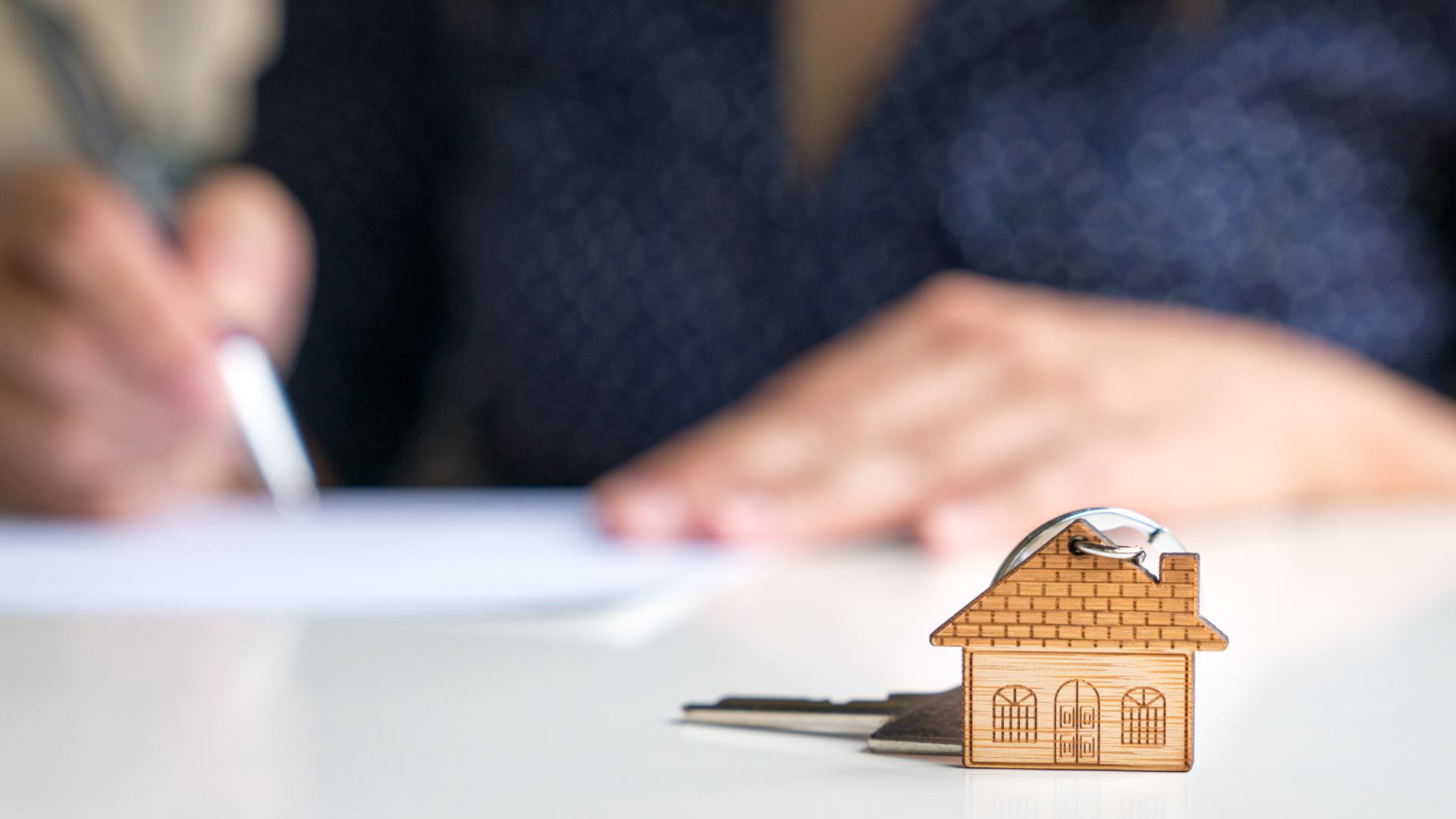 Immobilienbewertung – Vertragsunterzeichnung mit Schlüsselanhänger